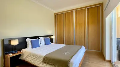 a bedroom with a large bed with blue pillows at Oura Oasis C by Check-in Portugal in Albufeira