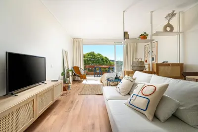 a living room with a white couch and a flat screen tv at Estúdio do Largo - Vilamoura in Vilamoura