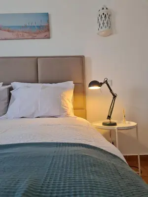a bedroom with a bed with a lamp on a table at Timi's House - Espaçoso apartamento a 350 m da praia e centro da cidade velha in Albufeira