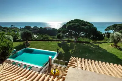 a house with a swimming pool next to the ocean at Villa Mauri Luxe - Beautiful beachfront villa in Albufeira