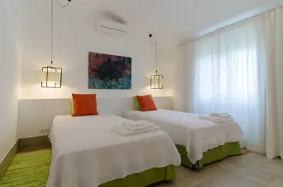 two beds in a room with white and orange pillows at Villa Colom in Quarteira