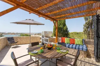 a patio with a table and chairs and an umbrella at Villa Colom in Quarteira