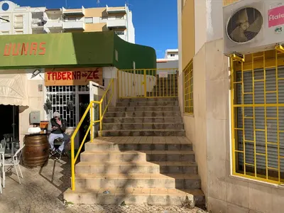 a stairway leading up to a building with a man sitting on a chair at Eine Wohnung für den perfekten Urlaub !!! in Quarteira