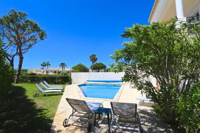 a patio with chairs and a swimming pool at Spacious Vilamoura Villa 4 Bedrooms Villa Amendoeira Table Tennis in Quarteira