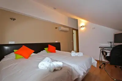 a bedroom with a white bed with orange and green pillows at Spacious Vilamoura Villa 4 Bedrooms Villa Amendoeira Table Tennis in Quarteira