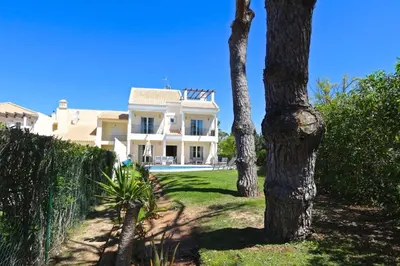 a large white house with trees in front of it at Spacious Vilamoura Villa 4 Bedrooms Villa Amendoeira Table Tennis in Quarteira