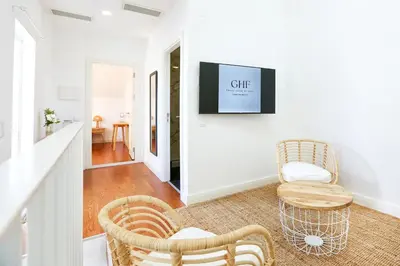 a living room with two chairs and a tv on the wall at Tropical Flavour Apartment in Faro