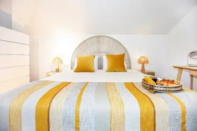 a bed with a striped blanket and a bowl of fruit on it at Tropical Flavour Apartment in Faro