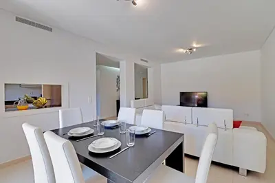 a dining room with a black table and white chairs at Victoria Garden in Vilamoura
