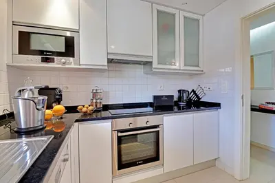 a kitchen with white cabinets and black counter tops at Victoria Garden in Vilamoura