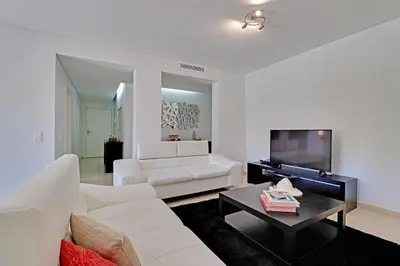 a living room with a white couch and a tv at Victoria Garden in Vilamoura