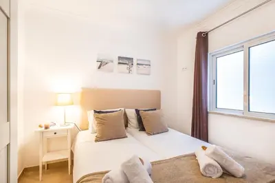 a white bedroom with a bed and a window at Casa Negril by Algarve Vacation in Albufeira