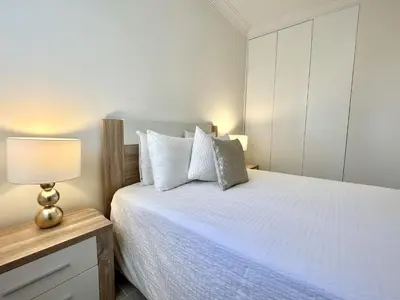 a bedroom with a white bed with a lamp on a dresser at Oceanview - Sea front by HD PROPERTIES in Quarteira