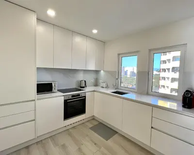 a white kitchen with white cabinets and a window at Oceanview - Sea front by HD PROPERTIES in Quarteira