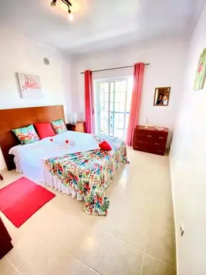 a bedroom with a large bed with red curtains at Flamingos Apartment with 2 swimming pool com check in e check out ao domingo em julho e agosto in Albufeira