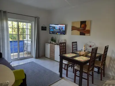 a living room with a table and chairs and a television at Flamingos Apartment with 2 swimming pool com check in e check out ao domingo em julho e agosto in Albufeira