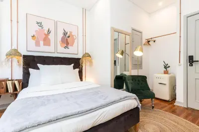 a bedroom with a large bed and a green chair at @ rita'splace in Faro