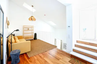 a living room with a yellow couch and a staircase at Zen & Tan Apartment in Faro