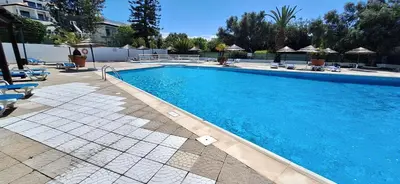 a large blue swimming pool with chairs and umbrellas at endless summer-with pool in Albufeira