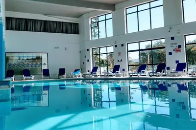 a large swimming pool with blue chairs in a building at Albufeira SPOT com piscinas exteriores e interior! in Albufeira