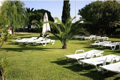 a row of white chaise lounges in a park at Albufeira SPOT com piscinas exteriores e interior! in Albufeira