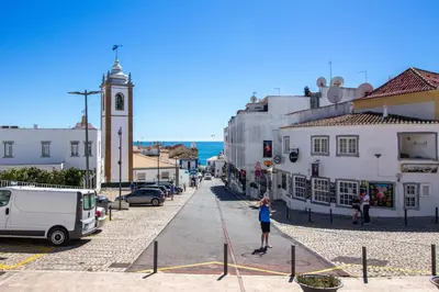 a woman is standing on a street in a town at Bay View Modern Apartment in Albufeira