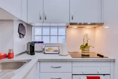 a kitchen with white cabinets and a sink at Faro: Casa Trevo com terraço BBQ in Faro