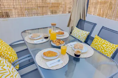 a glass table with plates of food and orange juice at Faro: Casa Trevo com terraço BBQ in Faro