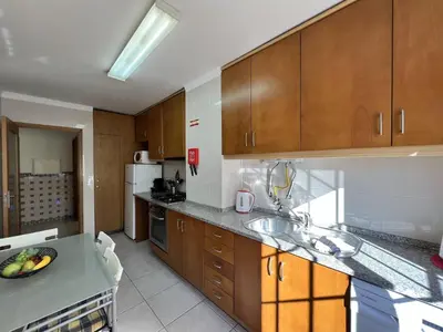 a kitchen with wooden cabinets and a counter top at Albufeira Brightness by Homing in Albufeira