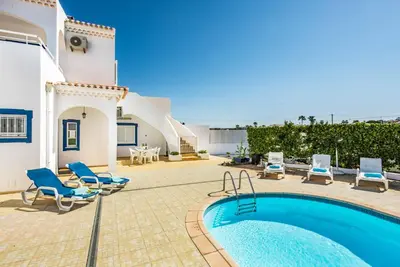 a villa with a swimming pool and blue chairs at Villa Dois Pinheiros in Albufeira