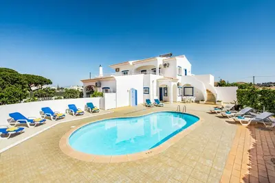 a villa with a swimming pool in front of a house at Villa Dois Pinheiros in Albufeira