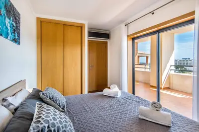 a bedroom with a bed with a couch and a balcony at Corcovada, Sunny and Bright T1 with Large Terrace, Albufeira in Albufeira