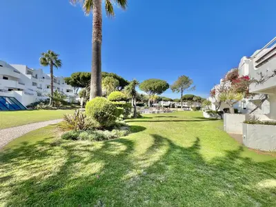 a green yard with palm trees and a building at Albufeira Balaia Golf Vilage 1 With Pool by Homing in Albufeira