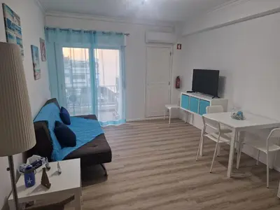 a living room with a bed and a table and a tv at Apartamento em Quarteira in Quarteira
