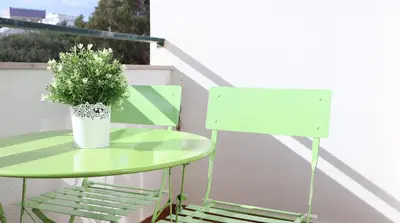 a green table and chair with a plant on a balcony at Visconde By Albufeira Rental in Albufeira