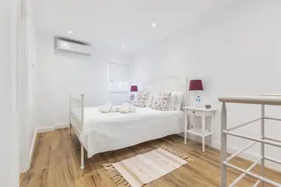 a white bedroom with a white bed and a table at RG Casa do Carmo in Faro