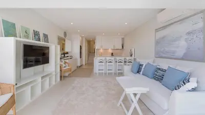 a living room with a white couch and a kitchen at Keiko in Vale do Lobo