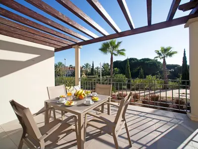 a patio with a table and chairs and a wooden pergola at Apartment Pine Hills Rubi by Interhome in Vilamoura