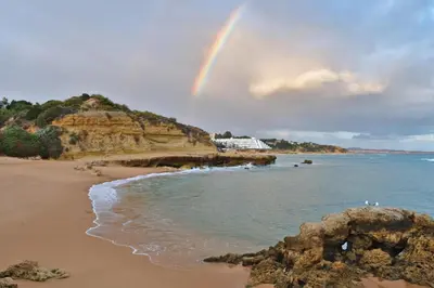 a rainbow over a beach with the ocean at 1-Bed - Sleeps 4 - Free Parking & Balcony in Albufeira