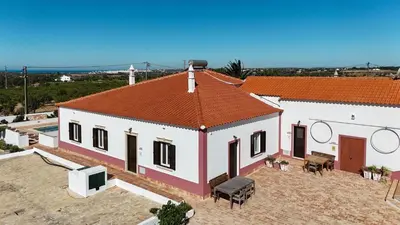a white building with an orange roof with a courtyard at Quinta Coelho in Guia