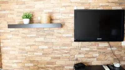 a flat screen tv hanging on a brick wall at Casa da Praia - São Rafael - BY BEDZY in Albufeira