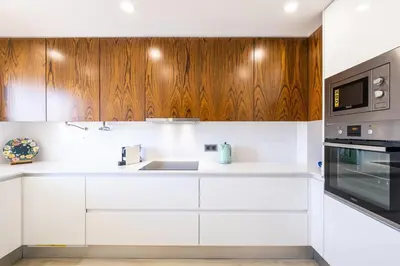 a kitchen with white counters and wooden cabinets at Benjamin Apartment in Guia