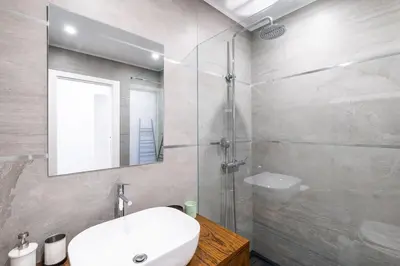 a bathroom with a sink and a shower with a mirror at Benjamin Apartment in Guia