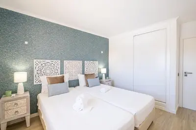 a bedroom with two white beds and a green wall at Benjamin Apartment in Guia