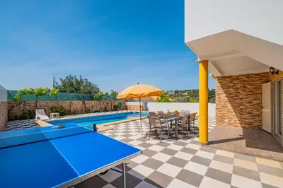 a patio with a ping pong table and an umbrella at Villa Duarte in Albufeira