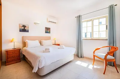a bedroom with a bed and a chair and a window at Villa Duarte in Albufeira