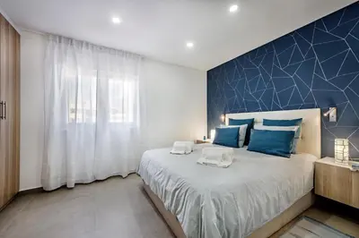 a bedroom with a large bed with a blue accent wall at Oura Sunset Apartement in Albufeira