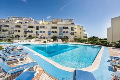 a swimming pool with lounge chairs and a building at Oura Sunset Apartement in Albufeira