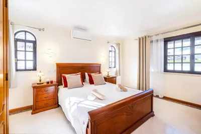 a bedroom with a large bed and two windows at Villa Molucas by Algarve Vacation in Albufeira