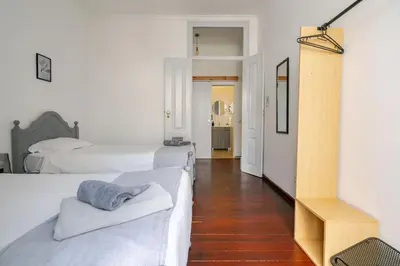a white bedroom with two beds and a hallway at Down Town Beach House in Albufeira